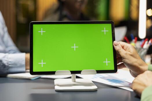 Close up of business team hosting a meeting with chroma key on tablet, late night briefing conference to discuss budget updates and performance metrics. Align company objectives for vision. photo