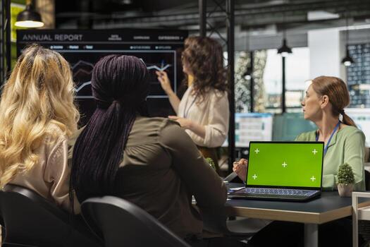 Determined diverse corporate team using display with chroma key, exchanging reports and strategy insights with data visualization. Work environment and productivity in office workspace. photo