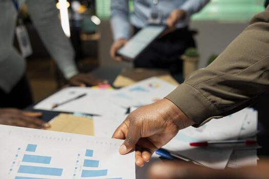 Close up of diverse project team shares analytics reports during advisory board event after hours, reviewing business intel and preparing insight for upcoming presentation with associates. photo