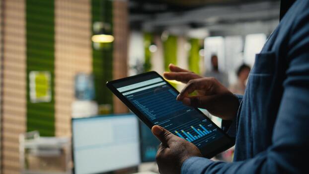 Close up of black employee engages in charts analysis session on tablet, leveraging data insights and reports to align the business strategy with goals for efficient project execution. photo