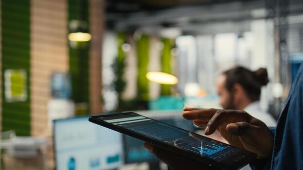 Close up of man reviews performance metrics insights on tablet, driving business strategy and innovation while maintaining a workplace efficiency. Focusing on objectives and success. photo