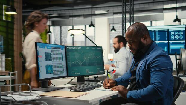 Black employee building new development strategy with notes, analyzing data and solutions to forecast project outcomes. Male professional working on briefing reports in the office. photo