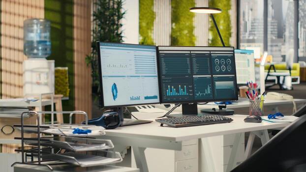 Empty business offices with dual monitors running financial diagnostics to help planning development strategy, data analytics and performance metrics. efficiency at the workspace. photo