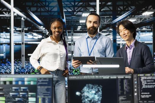 Portrait of multiethnic data center IT team running AI forecasting simulations, tracking performance. Smiling workers in diverse server hub using devices to integrate deep learning APIs photo