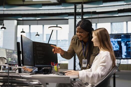 simpático mayor ingeniero mentoring alegre júnior dev a puesto de trabajo en oficina, revisando ai sistema métrica. contento africano americano gerente estrella de guía interno mediante código revisando utilizando máquina aprendizaje foto