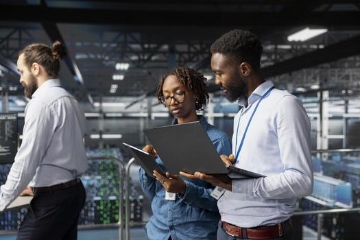 Black engineering team doing maintenance on servers used for AI processing. IT experts managing data center arrays to guarantee machine learning automation on laptop, visual analytics. photo