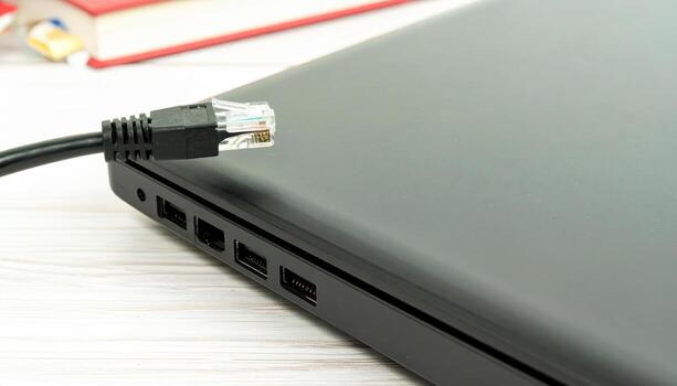 Macro close up of an ethernet cable plugged into a laptop with copy space background, suitable for technology themes, internet connectivity concepts, digital network visuals, IT projects, and modern photo