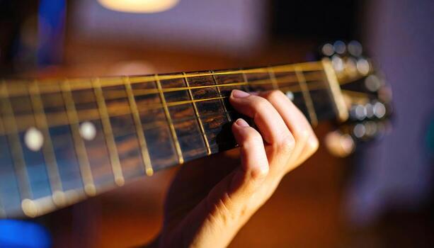 Close up photo of a musicians hands strumming guitar strings, highlighting artistic performance, live music, creativity, sound detail, and authentic instrumental atmosphere.