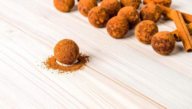 Flat lay photo of chocolate truffles with cocoa powder and cinnamon sticks, highlighting gourmet dessert, sweet indulgence, confectionery detail, rustic food styling, and elegant presentation.