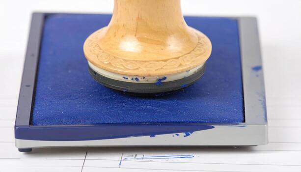 Macro close up of office stamp pressing an ink pad with copy space background, suitable for business themes, administration concepts, legal validation visuals, paperwork projects, official document photo