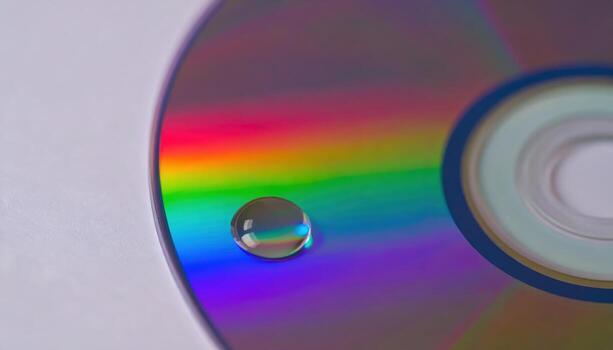 Macro close up of water droplet on CD rainbow reflection with copy space background, perfect for abstract design themes, colorful light projects, creative texture visuals, optical pattern studies, photo
