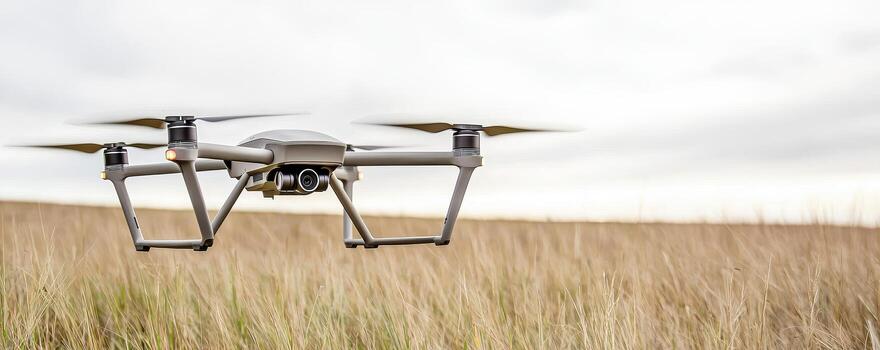 Drone flying over dry grass field with cloudy sky in background photo