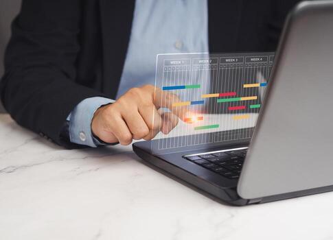 Close-up of a project manager working on a laptop and updating tasks and milestones progress planning. photo