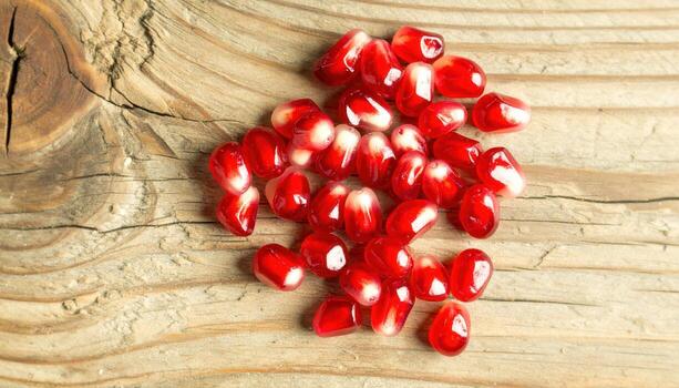 Vibrant Ruby Pomegranate Seeds on Textured Light Wood Grain Surface. photo