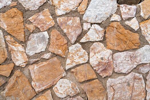 A close-up of a natural stone wall, showcasing its durable and rustic charm. Ideal for architecture and design projects, this texture adds visual appeal to backgrounds. photo