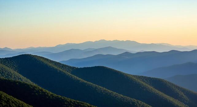 Layers of forested mountain ranges fading into the distance under a soft gradient sky photo