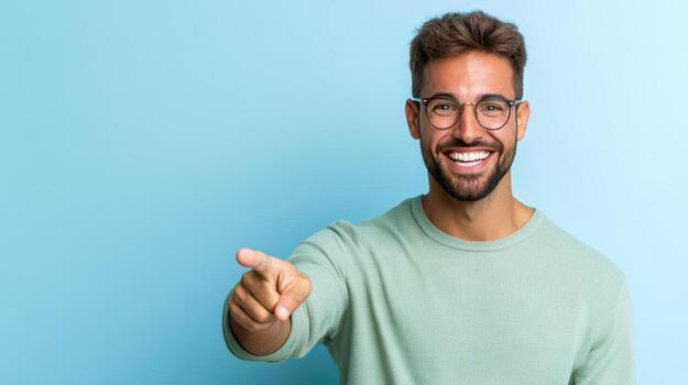 Cheerful man smiling and pointing at camera with excitement against blue background photo