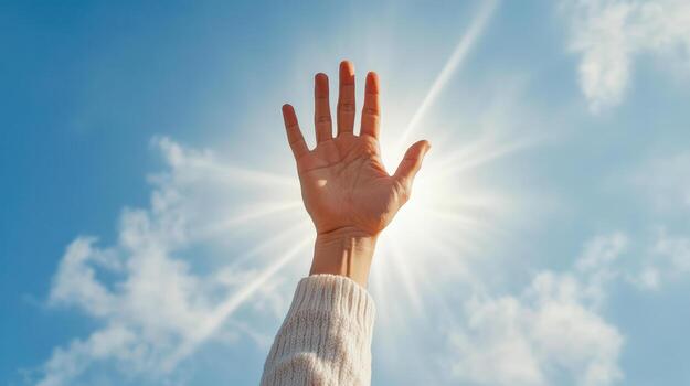 Reaching hand toward bright sky with sunlight streaming down, symbolizing hope and aspiration photo