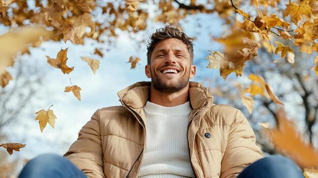 A man is laughing under a tree with autumn leaves photo