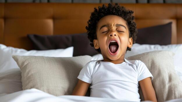 Yawning child in bed, cozy atmosphere, bedtime routine, sleepy expression, soft pillows photo
