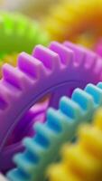 3D looped close up of bright plastic gears rotating within a large interconnected mechanism, with vivid colors and a soft focus effect. video