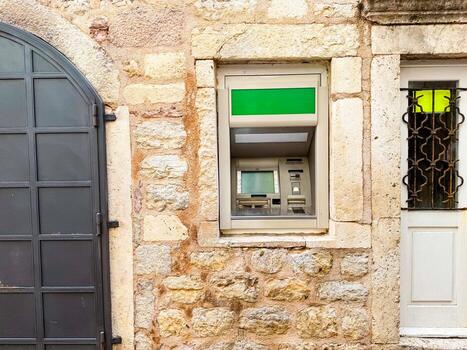 ATM machine installed in a stone building wall with visible access panel. Finance, banking service and secure urban technology system. photo
