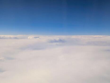 Expansive view of clouds under a clear blue sky from high altitude during flight near sunny weather photo