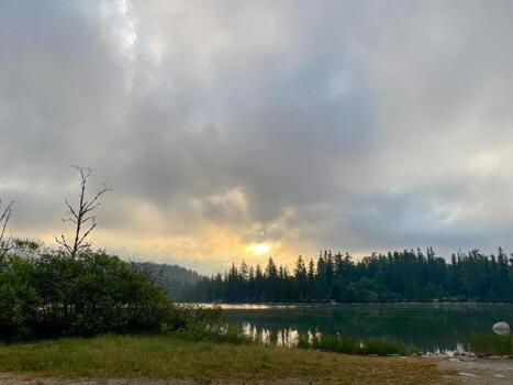 Dark dramatic clouds above forest lake with reflection at sunset. photo