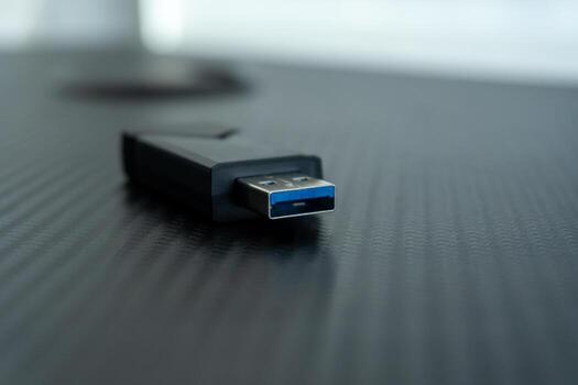 A USB drive is placed on a glossy surface, focused on the connection port. The scene is well-lit, highlighting the sleek design of the device photo