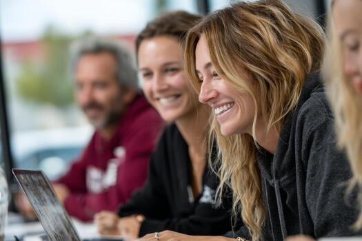 Three women are smiling while sitting at a table with laptops photo