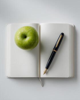Minimalist flat lay of open notebook with fountain pen and fresh apple on white background soft diffused light crisp focus professional office and study concept photo
