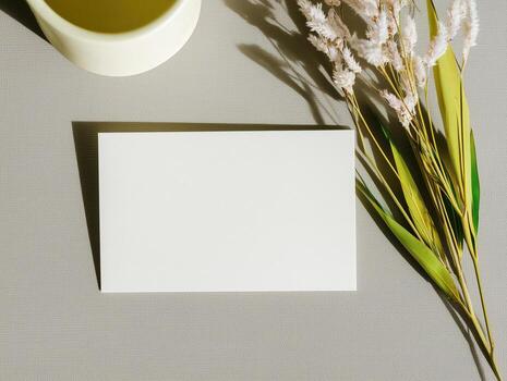 Elegant boho mockup of an invitation card placed on a textured surface with greenery and a cup photo
