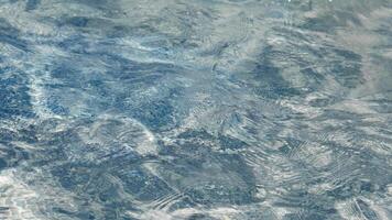 Soft sunlight dances on surface of clear water, creating shimmering patterns. Gentle ripples distort reflections, enhancing tranquil atmosphere of peaceful outdoor scene. Abstract pool water . video