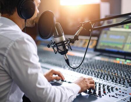Young radio host broadcasting in studio, focused on mixing audio with high fidelity equipment. atmosphere is vibrant and creative, capturing essence of live broadcasting photo