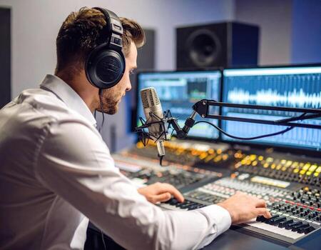 Young radio host broadcasting in modern studio, focused on mixing audio with high fidelity equipment. atmosphere is creative and energetic, showcasing art of sound production photo
