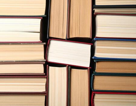 Stack of hardcover books various colors and sizes, creating visually appealing arrangement that evokes sense of knowledge photo