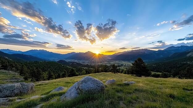 The sun sets over a mountain range with grass and rocks photo