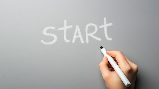 Creative hand writing start word on a gray surface with a white marker during a brainstorming session photo