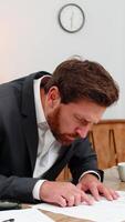 medelålders affärsman på Hem kontor läser kontrakt små text med förstoringsglas finner fel och skakningar huvud Nej. frilansare kille på tabell skrivningar brådskande fixera på klistermärke och uppsättningar notera för uppdatering detta tid. video
