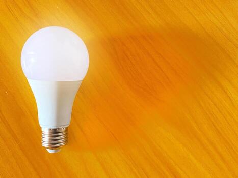 Energy efficient light bulb rests on a textured golden casting a soft glow photo