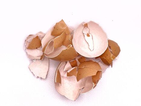 Cracked eggshells scattered on a white create a delicate and discarded still life. photo