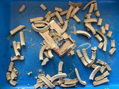 Broken ceramic pieces and metal fragments scattered on a textured blue create abstract art photo