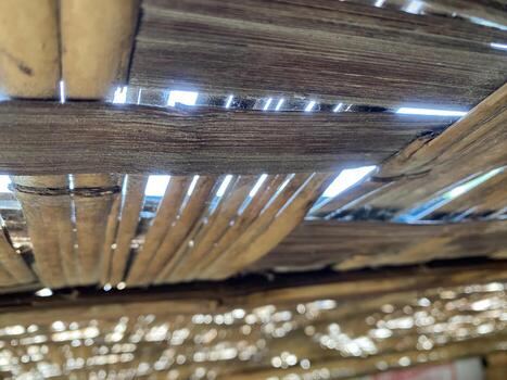 Woven bamboo creates a textured ceiling with bright sunlight filtering through the gaps. photo