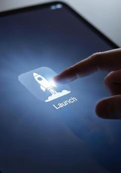 Finger touching a tablet screen with a rocket launch icon photo