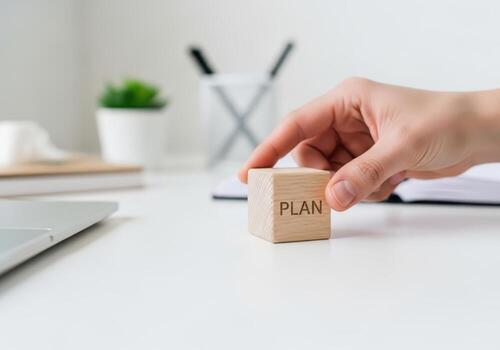 Hand placing wooden block with word plan on it on desk photo