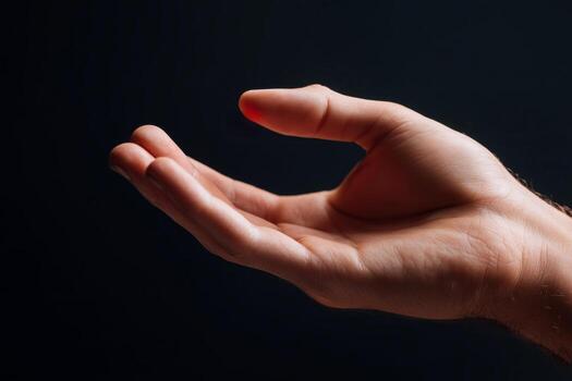 Open palm reaching towards the light against a dark backdrop, symbolizing openness and potential in a moment of stillness photo