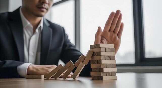 Businessman Preventing Domino Effect With Hand photo
