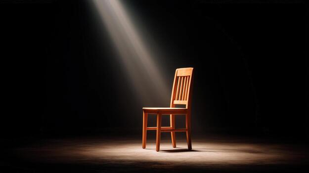 A chair in the dark with light shining from the top photo