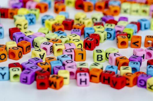 A focused display of glowing multicolored translucent cubes with black letters arranged messily on a clean white background reflecting fun and knowledge photo