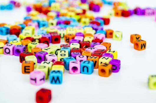 A close up view of vibrant multicolored translucent cubes with alphabet letters scattered across a white surface creating a playful and educational arrangement photo